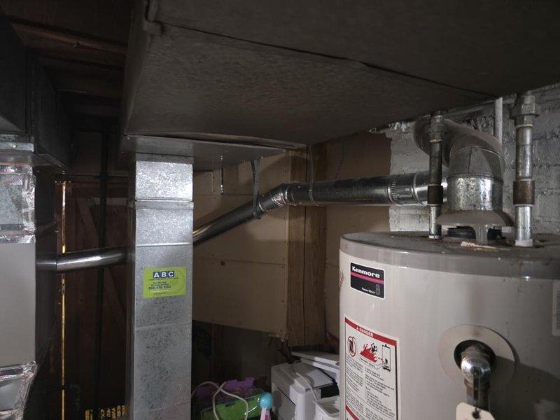 Conducted site assessment of basement mechanical room to evaluate ductwork modifications for improved clearance and safety. Evaluated existing galvanized ductwork configuration and HVAC equipment placement to determine feasibility of reducing duct dimensions from 8 inches to 4 inches on one side to eliminate head hazard concerns. Assessed options for repositioning ductwork against wall or relocating to bedroom area to provide adequate clearance above sleeping space. Evaluated potential relocation of furnace unit closer to side room to improve space utilization and reduce obstruction in main basement area. Documented existing installation including water heater, air handling unit, copper piping, and ductwork connections. Provided recommendations for ductwork reconfiguration while ensuring compliance with applicable building codes and maintaining proper airflow requirements for system performance.