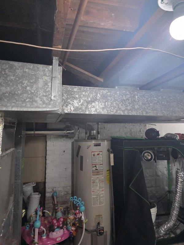 Conducted site assessment of basement mechanical room to evaluate ductwork modifications for improved clearance and safety. Evaluated existing galvanized ductwork configuration and HVAC equipment placement to determine feasibility of reducing duct dimensions from 8 inches to 4 inches on one side to eliminate head hazard concerns. Assessed options for repositioning ductwork against wall or relocating to bedroom area to provide adequate clearance above sleeping space. Evaluated potential relocation of furnace unit closer to side room to improve space utilization and reduce obstruction in main basement area. Documented existing installation including water heater, air handling unit, copper piping, and ductwork connections. Provided recommendations for ductwork reconfiguration while ensuring compliance with applicable building codes and maintaining proper airflow requirements for system performance.