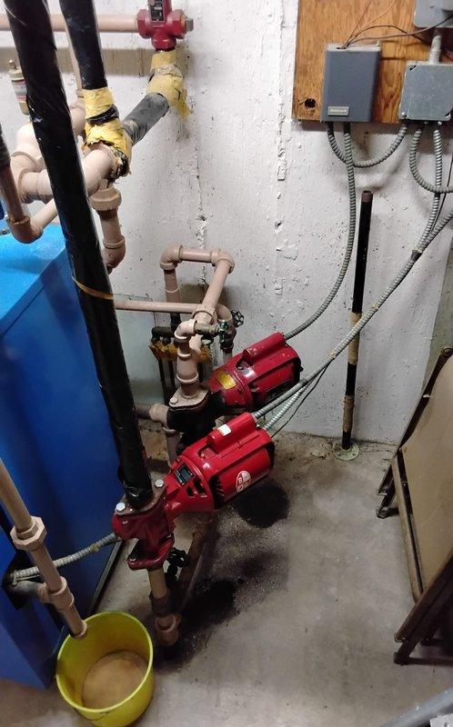 Responded to emergency water leak in mechanical room where radiator had been physically impacted, causing active water discharge. Upon arrival, assessed damage to heating system piping and immediately shut off water supply to affected radiator to stop leak. Inspected circulator pumps, pressure tank, and associated copper piping for additional damage or compromised connections. Coordinated with office to obtain property management approval for repairs per building protocols. Repaired damaged radiator connection point, replaced affected fittings, and restored water supply to system. Tested all connections for leaks, verified proper system pressure, and confirmed circulator pumps were operating correctly. Documented mechanical room conditions with photographs showing piping configuration, pump assembly, and repair location for records.