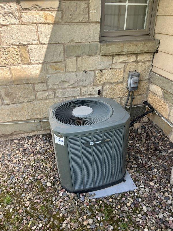 Conducted comprehensive evaluation of existing HVAC system for complete replacement estimate. Assessed current furnace installation in basement mechanical room, noting accessible location and existing ductwork configuration with metal plenum connections. Evaluated outdoor Trane condensing unit positioned on concrete pad with river rock landscaping against exterior wall. Documented equipment specifications, installation conditions, and spatial requirements for proposed Trane brand furnace and air conditioning system replacement to meet customer preferences.