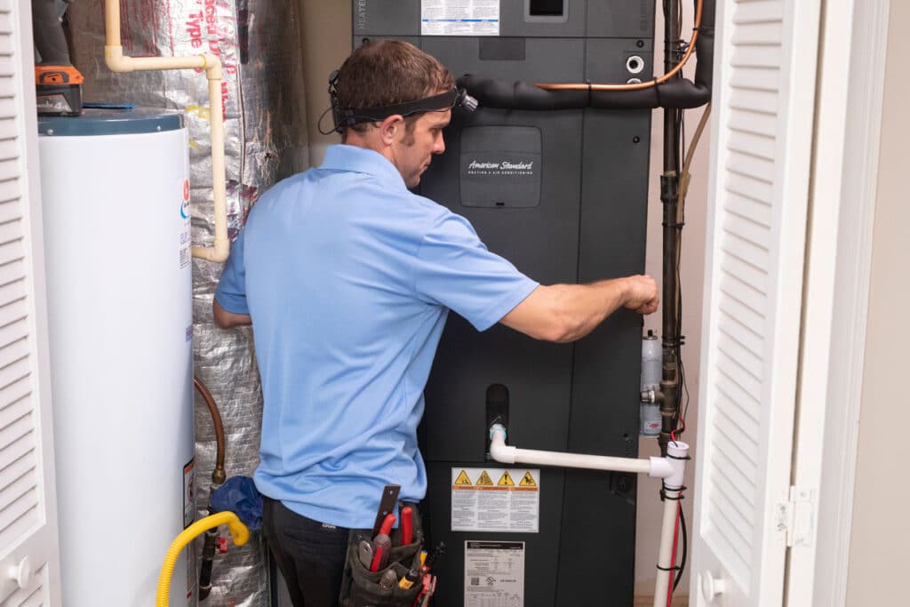 Home Comfort technician installing a heat pump front pane
