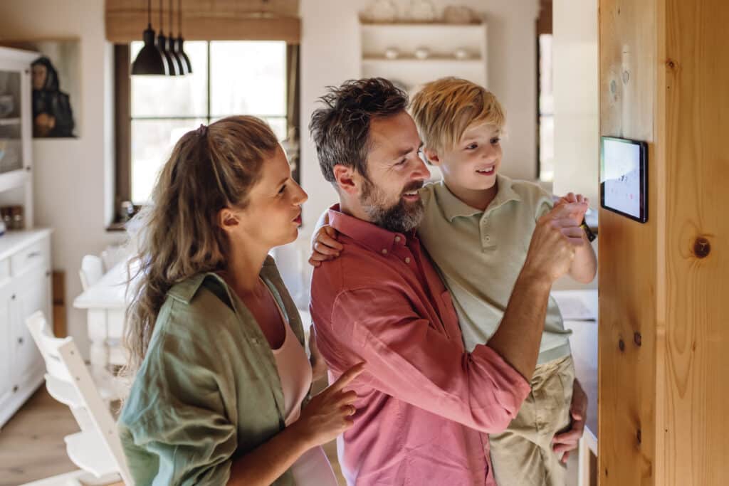 Family learning to use wireless smart thermostat in home
